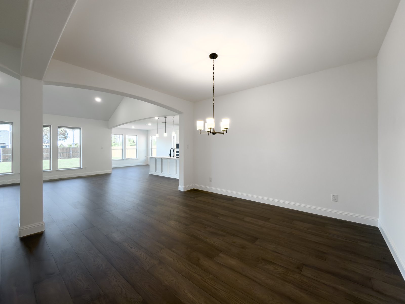 open dining room with wood floors and arch opening