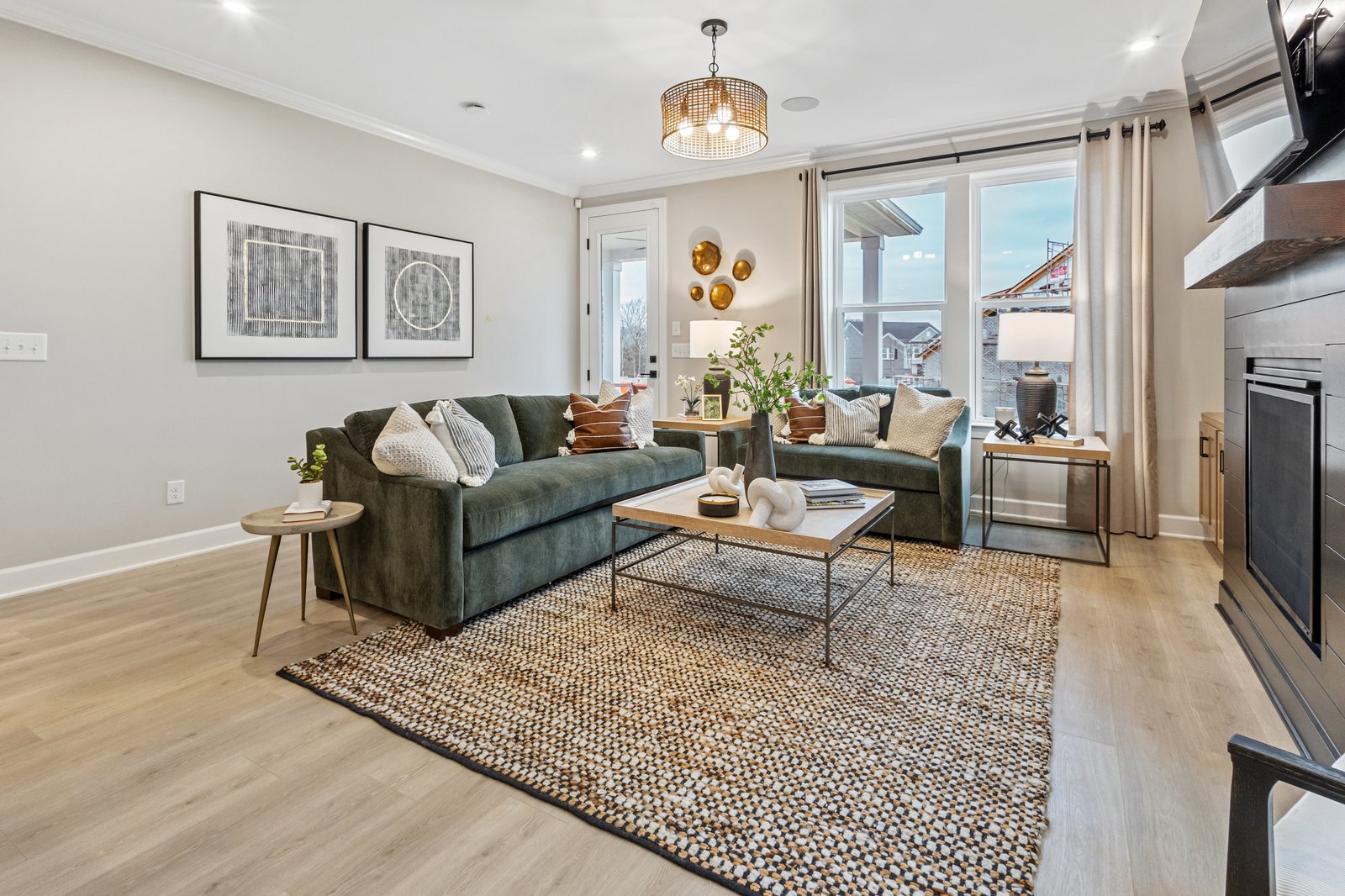 great room with hardwood floors, two green couches, and a shiplap accent fireplace