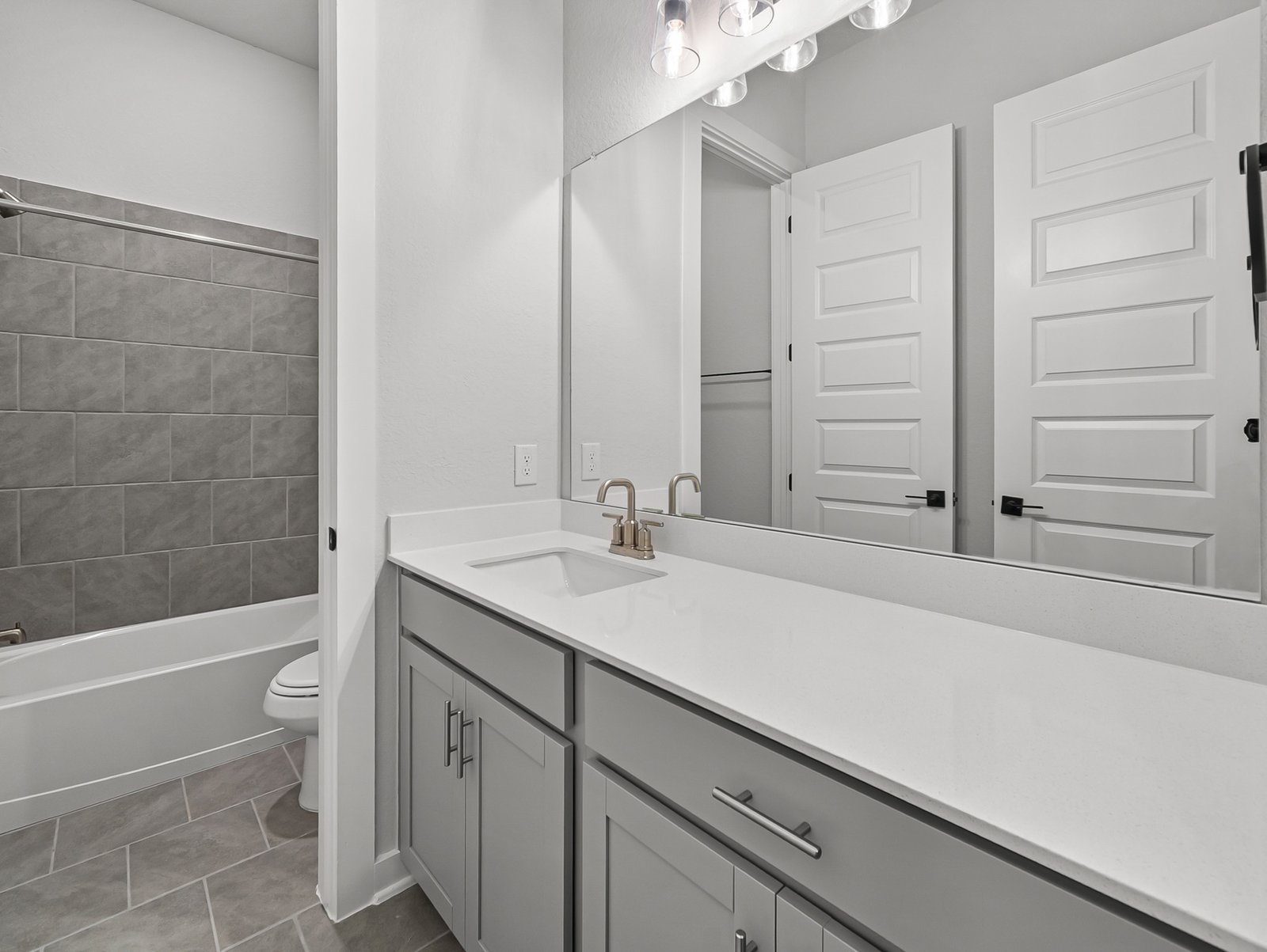 bathroom with quartz countertops & a tub with shower combo