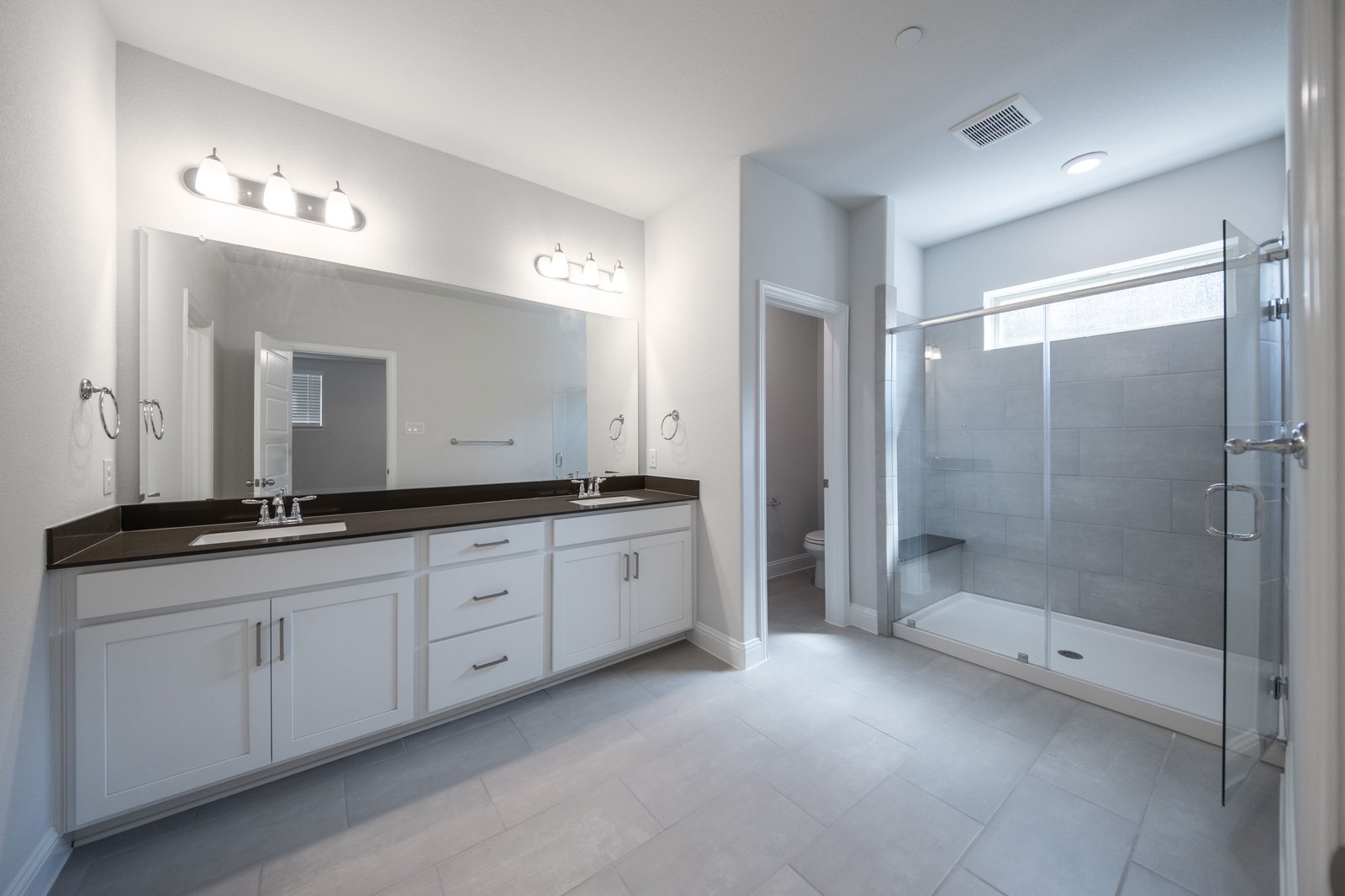bathroom with large walk-in shower and white cabinets