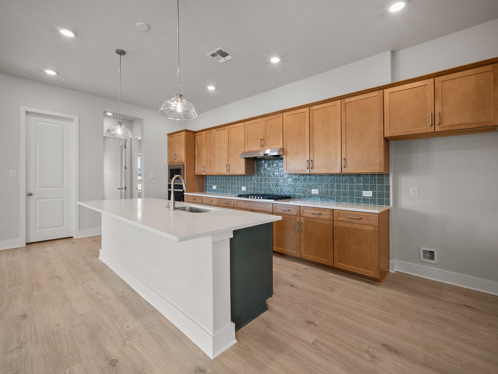 kitchen with quartz countertops, green backsplash & pendant lighting