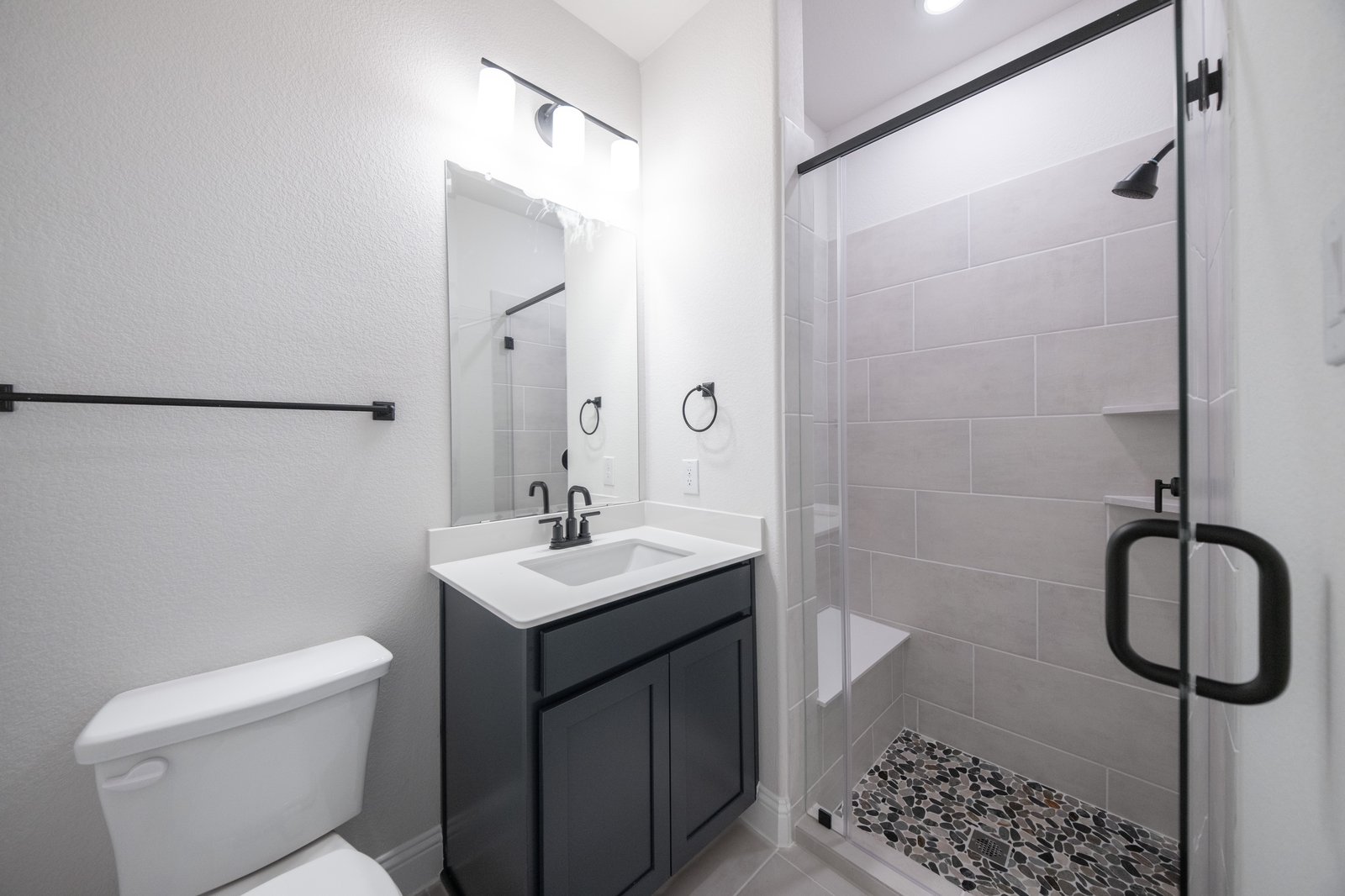 bathroom with walk-in shower and dark cabinets