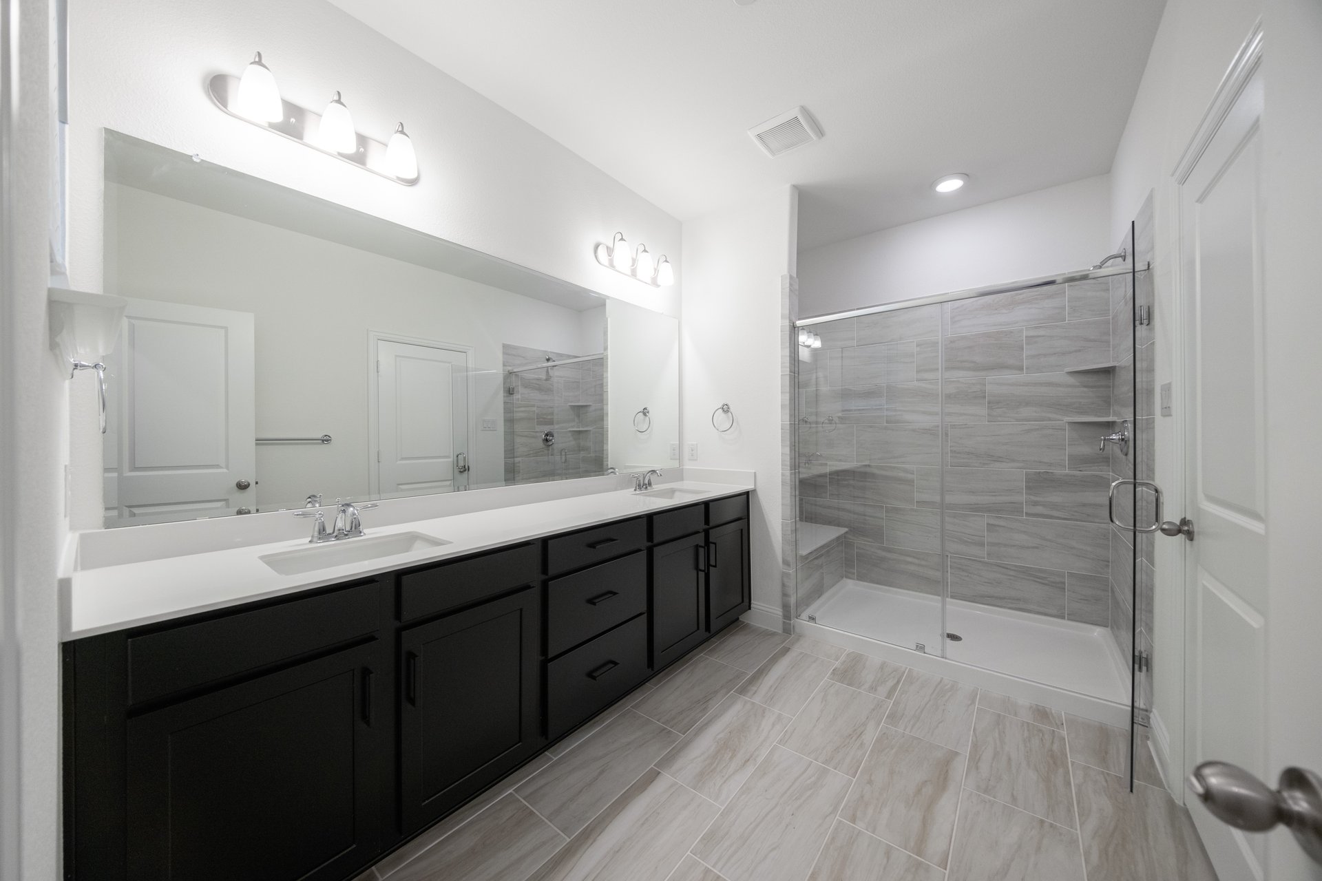 bathroom with large walk-in shower and black cabinets 