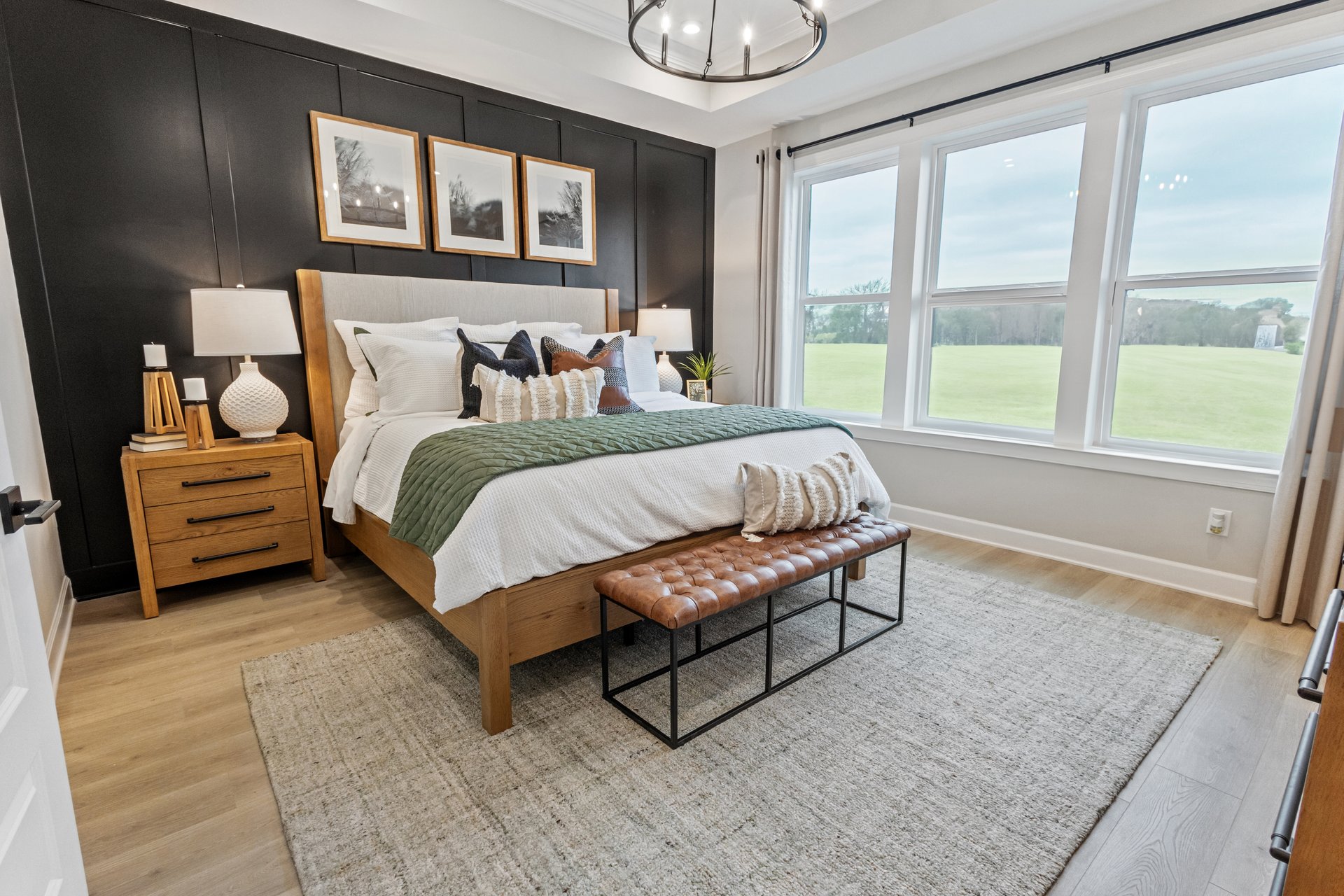 primary bedroom with hardwood floors, a large bed, and a black accent wall