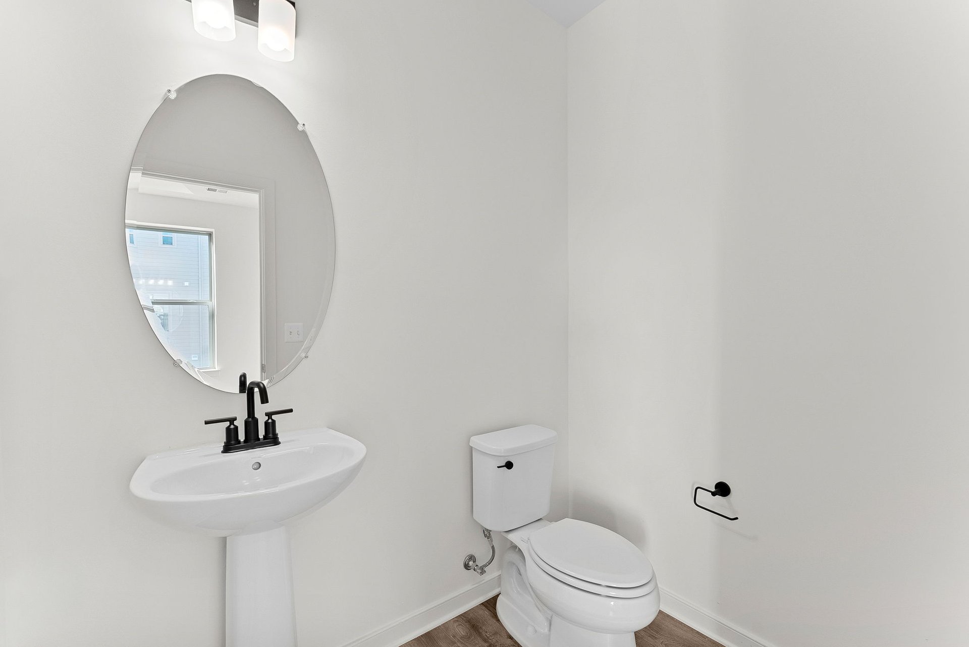 bathroom with toilet and mirror and sink and faucet underneath