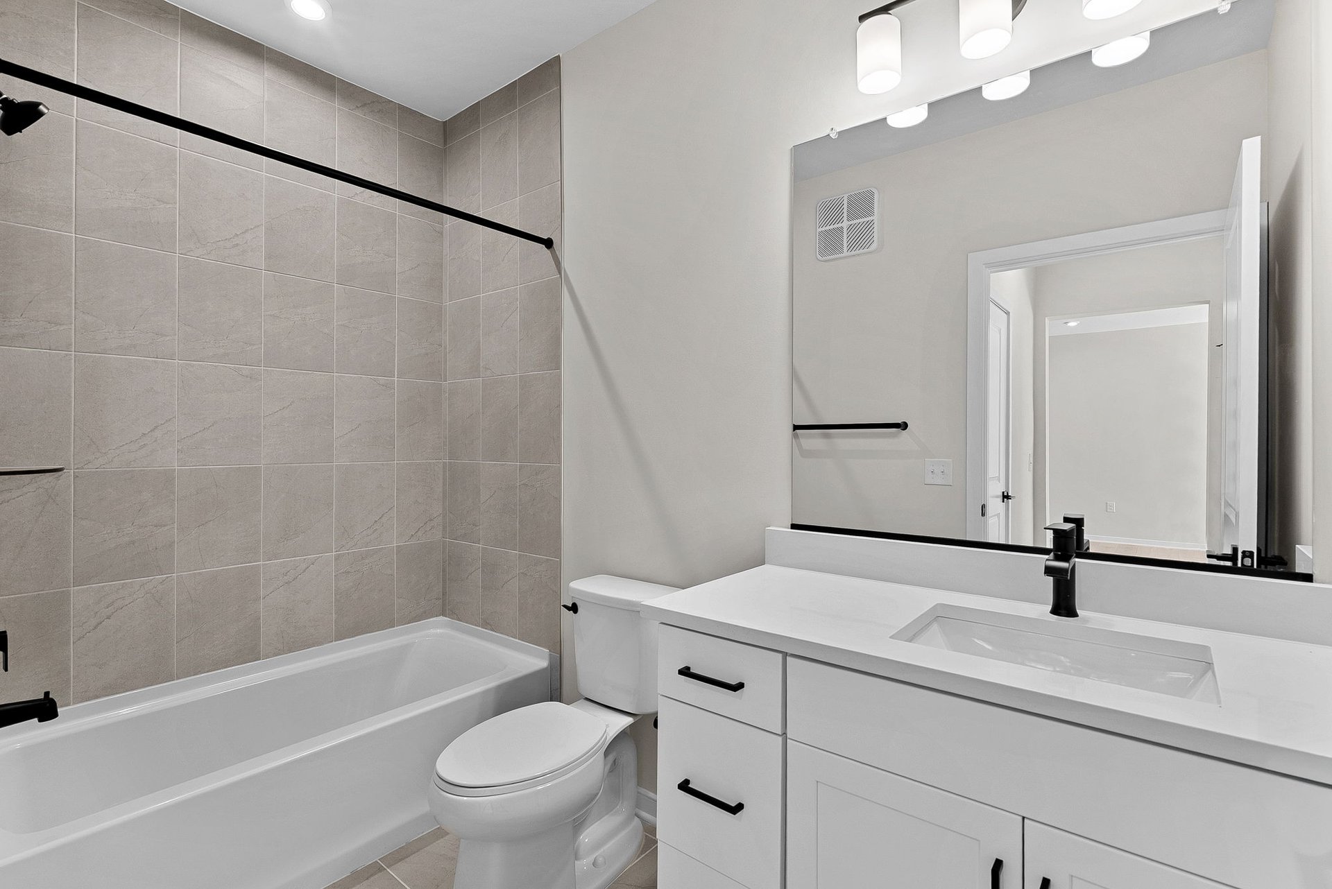secondary bathroom with shower, tub, black hardware in sink