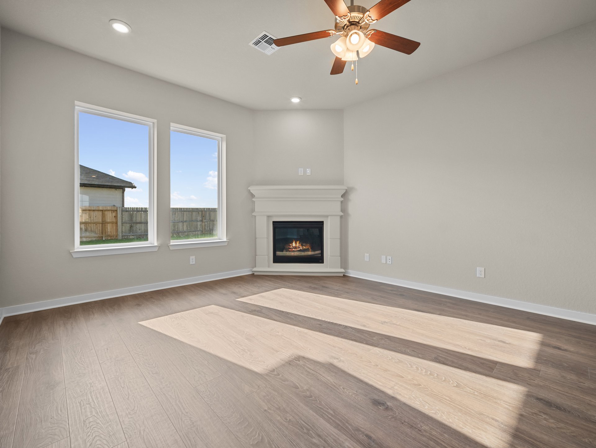 great room with brown flooring, windows & a fireplace