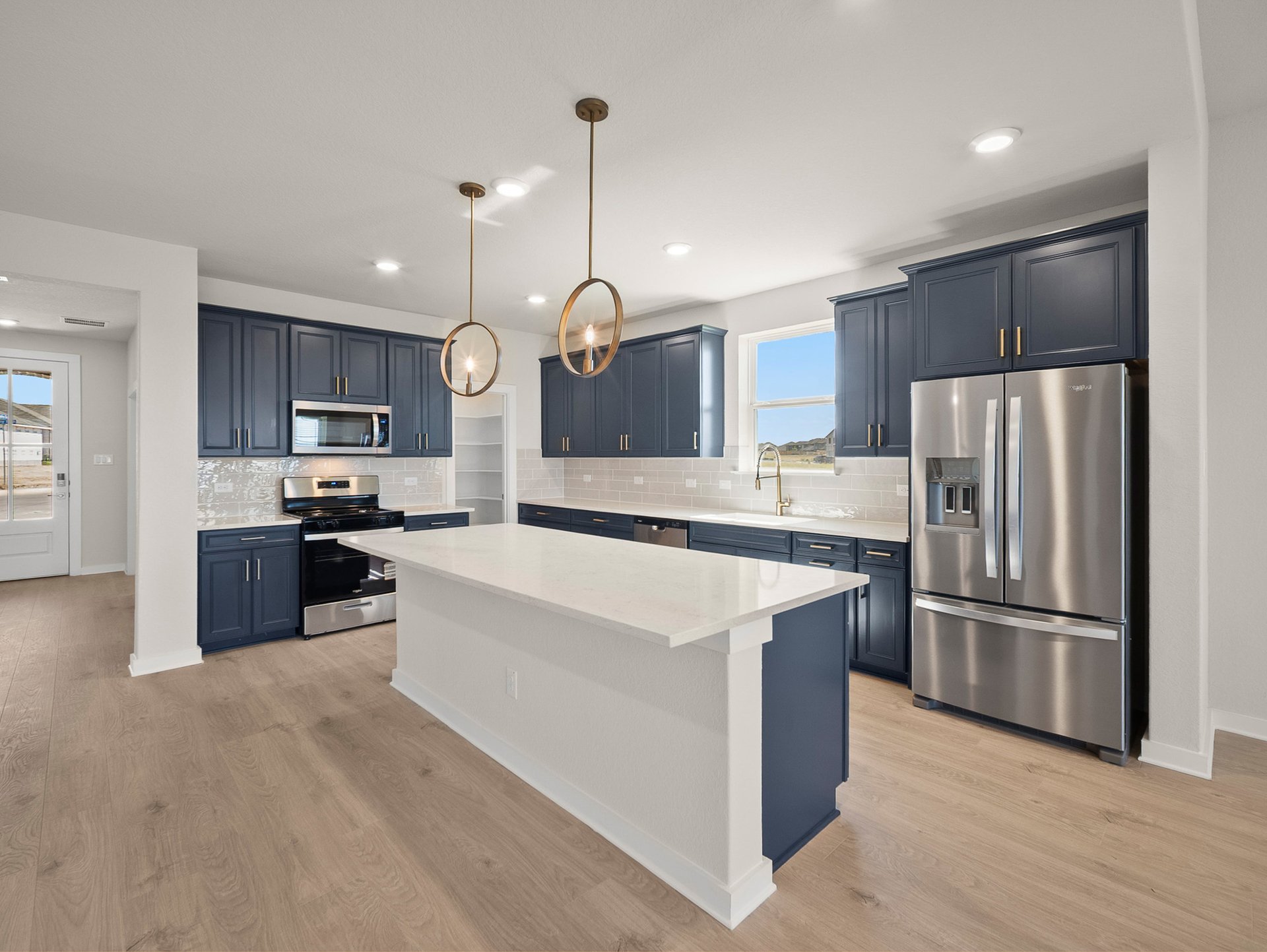 kitchen with blue cabinets, quartz countertops & pendant lighting