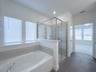 primary bathroom with separate soaking tub and walk-in shower