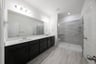bathroom with large walk-in shower and black cabinets 