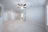 spacious loft with carpet and ceiling fan