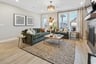 great room with hardwood floors, two green couches, and a shiplap accent fireplace