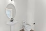 bathroom with toilet and mirror and sink and faucet underneath