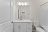 secondary bedroom with white cabinets, sink, and mirror