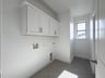 laundry room with tile floors and white upper cabinets