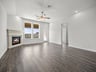 great room with brown flooring, windows & a ceiling fan