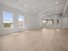 great room with brown flooring, windows & a ceiling fan