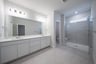 spacious primary bathroom with double sinks and walk-in shower