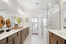 primary bathroom with tile flooring, a walk-in shower, and direct access to the walk-in closet