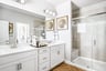 bathroom with walk-in shower and white cabinets 