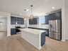 kitchen with blue cabinets, quartz countertops & pendant lighting